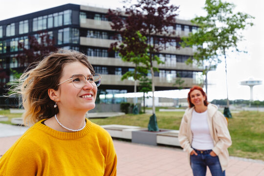 Happy young woman with mother standing at footpath