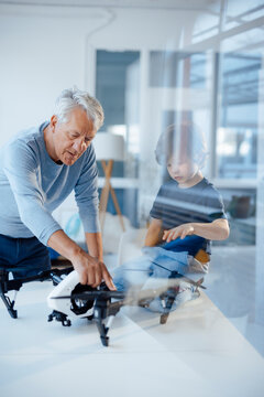 Senior man examining drone by grandson at home