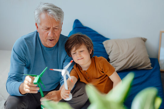 Grandfather and grandson holding wind turbine models in living room at home