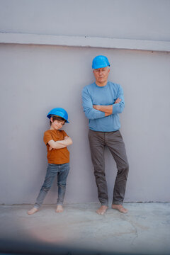 Confident senior man and grandson with arms crossed in front of wall