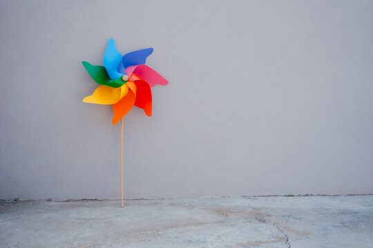 Multi colored pinwheel toy in front of gray wall