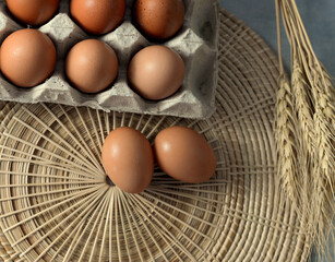 Top view of eggs in a paper tray Placed on wicker Garnish with dried barley.