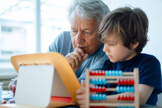 Senior man using tablet PC by grandson at home