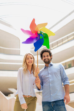 Happy business colleagues holding multi colored pinwheel toy