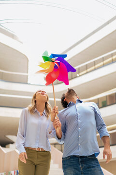 Playful business colleagues blowing multi colored pinwheel toy