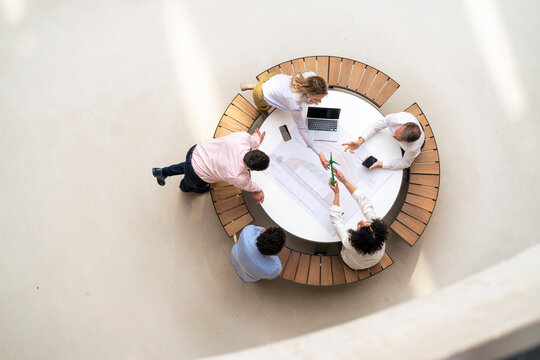 Business colleagues planning over wind turbine sitting on table in office lobby