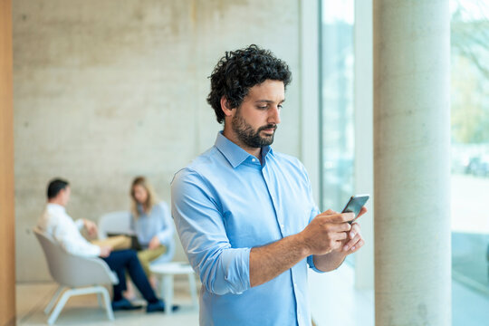 Businessman text messaging through smart phone at office