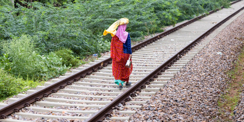 Mujer india con vestiduras tradicionales caminando por la vía del tren. 5-8-2022.