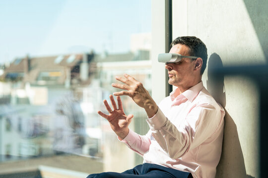 Mature businessman with futuristic glasses gesturing in office