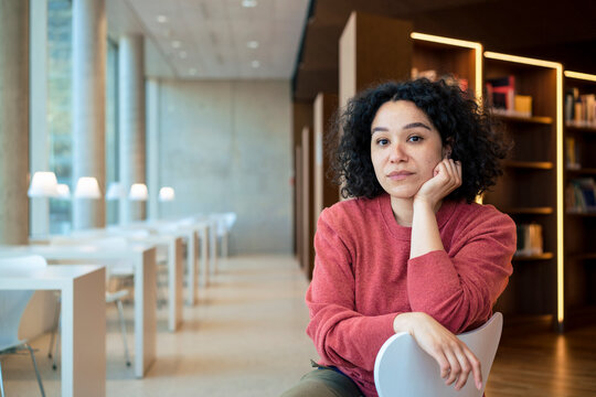 Woman with hand on chin at illuminated library