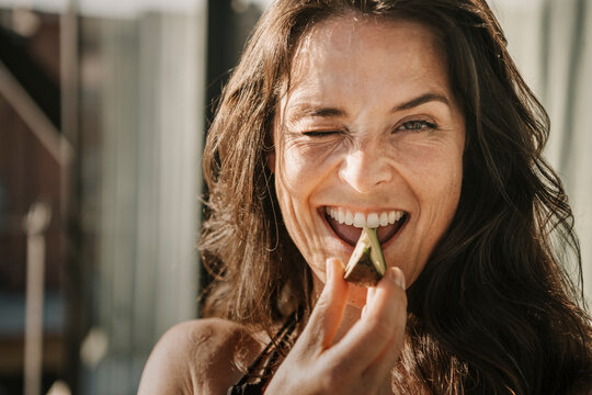 Woman With Winking Eye Biting Avocado Slice