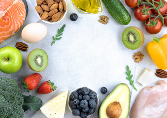 Keto diet background. Ingredients for the keto diet: green vegetables, fruits, berries, nuts on a gray background.