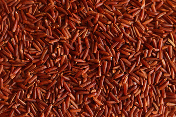 Dry uncooked brown wild rice as a background . Red grains, a stack of cereals. Organic natural ingredient for a healthy food.