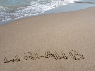 Schrift im Sand "Urlaub" Symbol