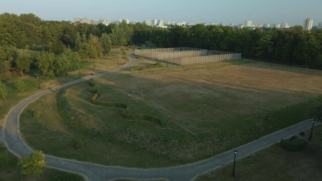 Ground sports grounds in the city park. With a mesh fence. City park at dawn. Aerial photography.