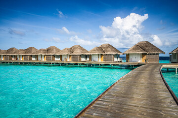 Luxury resort with water villas turquoise ocean lagoon seascape. Wooden pier pathway, idyllic sky....