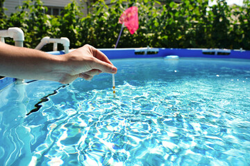 Checking the water quality of a pool with the help of a test strip with PH value, chlorine and...