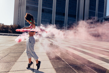 Woman with smoke grenade outdoors in city - obrazy, fototapety, plakaty