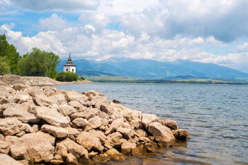 Fototapeta premium Water reservoir Liptovska Mara in the Slovakia. Old church in the Liptov region with Tatras background.