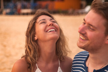 Portrait smiling lovely couple having fun on tropical sandy beach at palm trees background. Happy man and woman laughing happiness. Joyful couple enjoying summer at ocean coastline. Copy text space