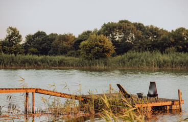 a quiet place for relaxation and fishing on the river in the summer at dawn. wooden pier and walkways. jetty with wooden chairs. nature in the village