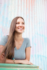 Happy long hair woman spending time on street standing by colorful pastel background. candid portrait