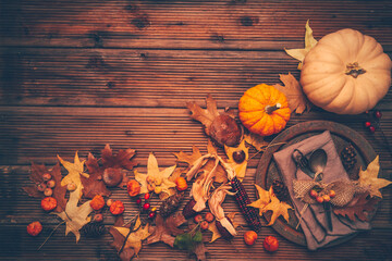 Autumn background with pumpkins, cutlery and golden leaves on a wooden surface
