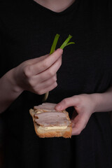 Closeup image of sandwich with soft cheese and pork in the hands of a teenager in a black T-shirt. healthy homemade snack.
