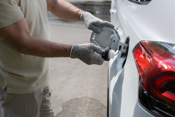man opens the hatch of the gas tank of the car