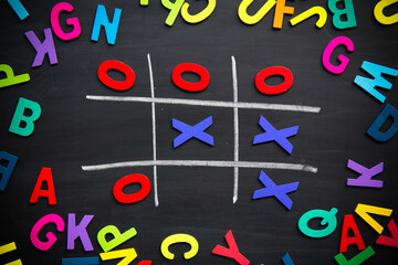 Abstract Tic Tac Toe Game Competition with Wood Alphabet letters. XO Win Challenge Concept on black board.