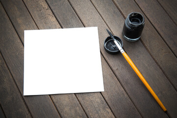 Abstract white paper with bamboo calligraphy brush and inkstone on old wooden table. picture for add text or greeting card chinese new year. Chinese traditional painting text