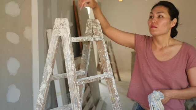 Exhausted asian woman standing in construction site. Tired woman with pair of work gloves.