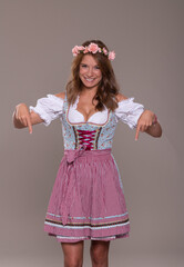 Junge Frau im Dirndl Kleid zeigt nach unten