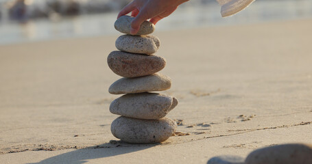 Fototapeta na wymiar Woman build zen stone tower with pebble stone