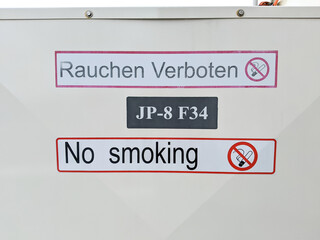 No smoking sign in English and German. Outdoor sign prohibiting smoking in red and white