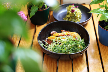 Stewed chicken liver with apple, served with pickled cucumber salad. Lunch served in a modern bowl on a wooden table.