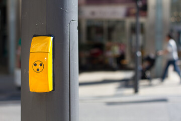 Yellow pedestrian traffic light button with blurred background