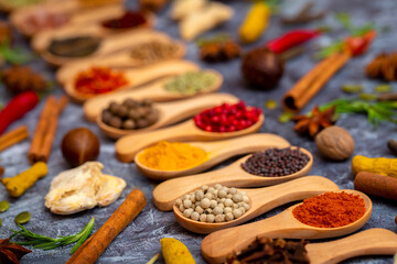 A set of spices on a gray background. Variety of spices from India. Food decoration design. Various spices, peppers and herbs close-up top view. Set of peppers, salt, herbs and spices for cooking.