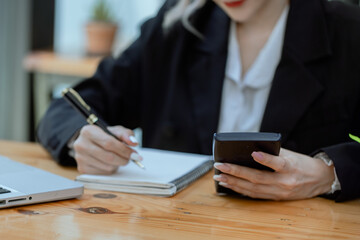 Businesswoman working with calculator and laptop computer at office workplace, finance marketing chart, Business digital technology and marketing concept.