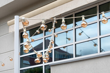 Light garland on the street at daylight. Decoration of the street with vintage Edison bulbs...