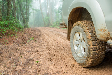 Fototapeta na wymiar Wheel truck closeup in countryside landscape with muddy road. Extreme adventure driving 4x4 vehicles for transport or travel or off-road races in outdoor nature. 4wd tire automobile on dirt mountain.