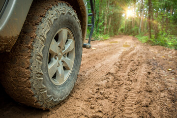 Wheel truck closeup in countryside landscape with muddy road. Extreme adventure driving 4x4 vehicles for transport or travel or off-road races in outdoor nature. 4wd tire automobile on dirt mountain.