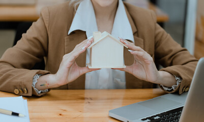 Businesswoman holds a house model, Business home loan and insurance concept.