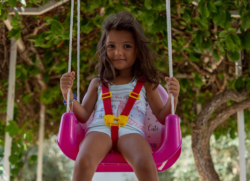 girl on the swing. pretty little girl is very happy on the swing. cute kid swinging. a green ivy tree in the background. Paid outdoor parks, children's playgrounds and kindergartens can use this pic