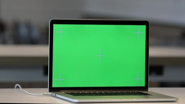 Laptop on the Desk in the Office Shows Green Mock-up Screen. In the Background Bright Creative Open Space Loft Office HUB with Professional Working