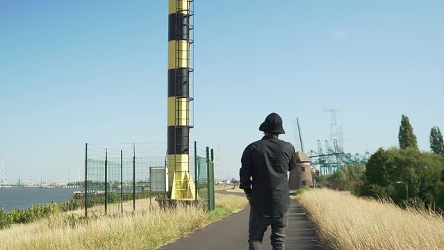 Hispanic guy walking on the road near the port of Antwerp, Belgium.