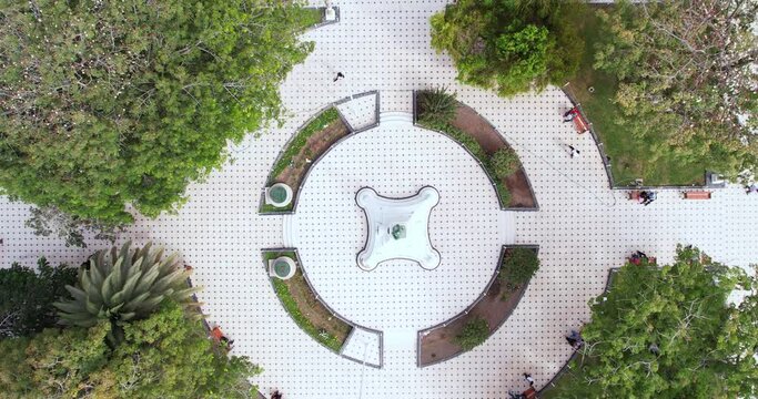 Amazing and beautiful drone zoom out of a circular park with trees in the city of Chiclayo, Peru during the day.