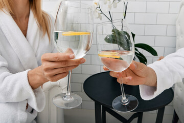 Young couple drinking water with lime from glasses while relaxing in spa to restore their body