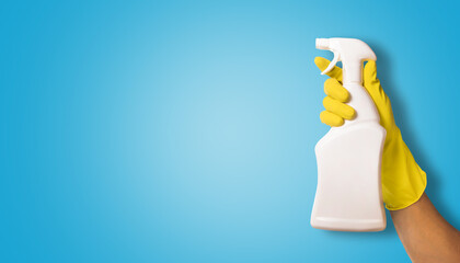 hand in yellow rubber glove holding white blank cleaning spray bottle on blue background. copy space - Powered by Adobe