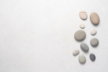 Fototapeta na wymiar White background with gray pebble stones. Top view, beauty, spa concept